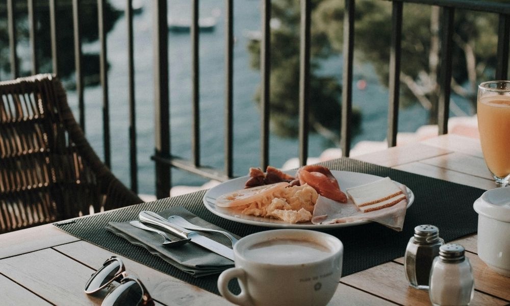 Tisch mit Frühstück auf einer Terrasse mit Blick auf Wasser